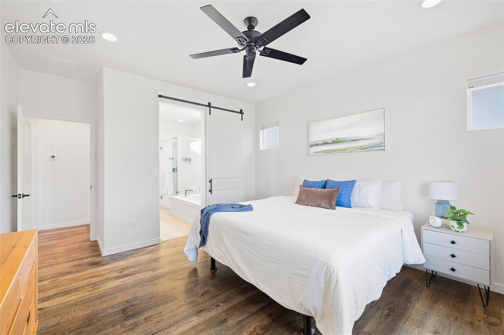 Image 17 of 46: A barn door keeps the primary bedroom and ensuite bath separate. 