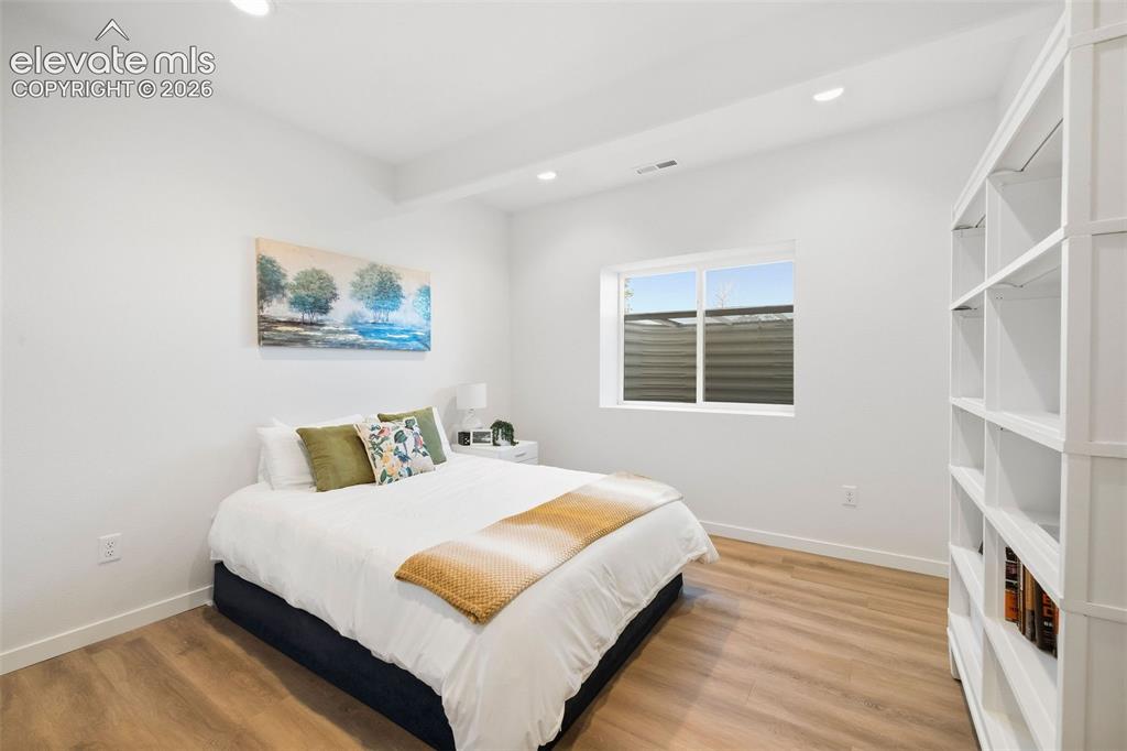 Image 28 of 46: One of two lower-level bedrooms, featuring built-in shelving and a window f