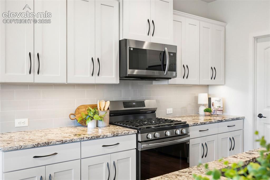 Image 6 of 46: The appliances include a five-burner gas range with an overhead vent/microw