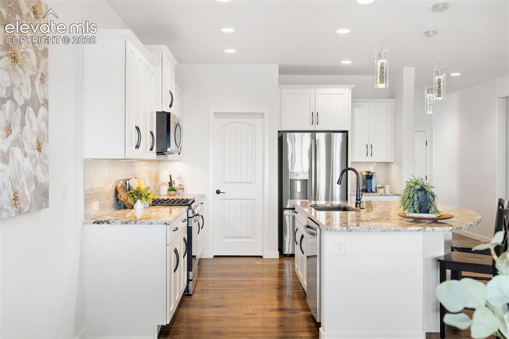 Image 7 of 46: View of the kitchen from the dining area. Real hardwood floors continue thr