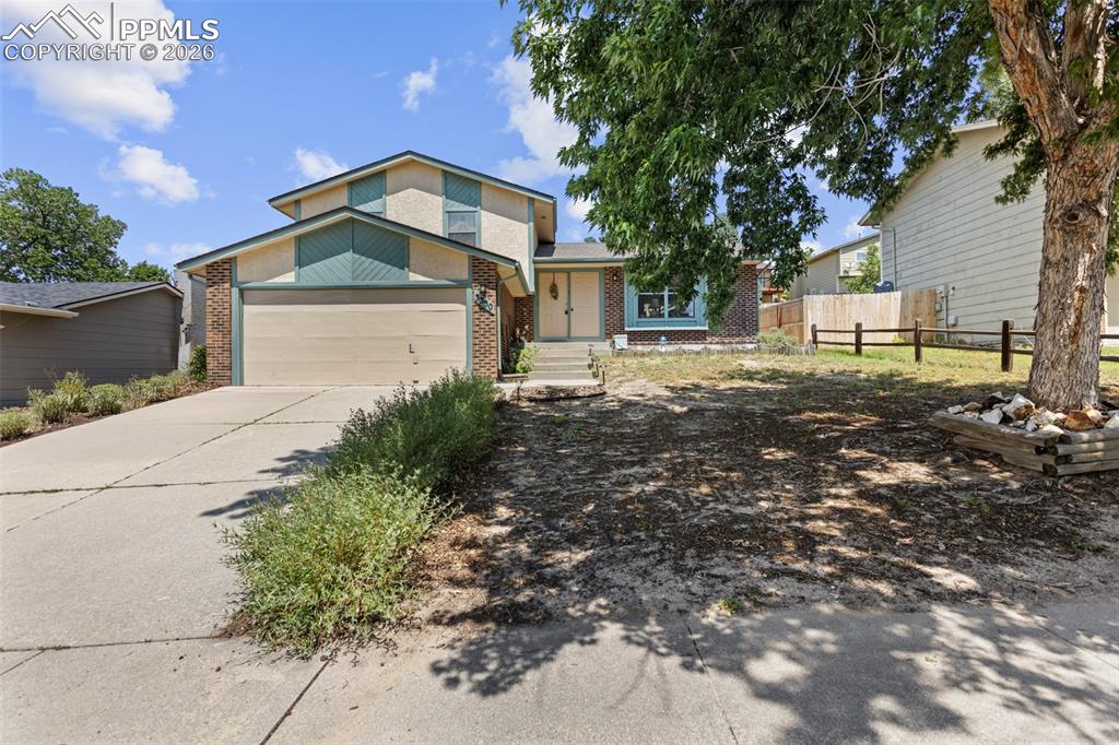 Caption: View of front of home with brick siding, a garage, and concrete driveway