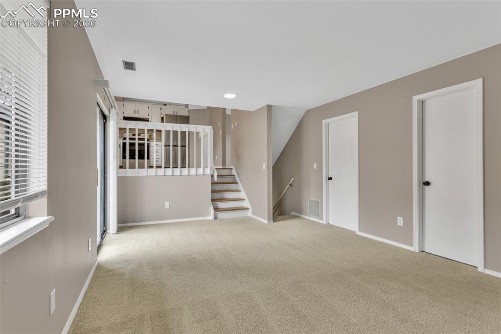 Image 11 of 30: Unfurnished living room featuring light colored carpet and stairs