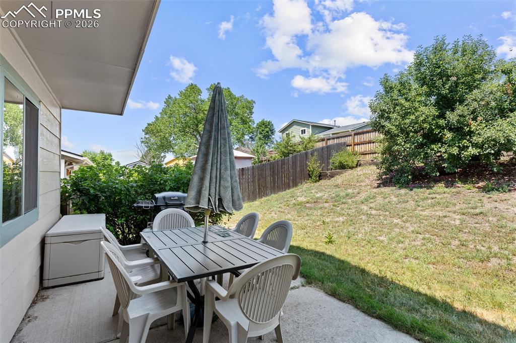 Image 27 of 30: Fenced backyard with a patio area and outdoor dining space