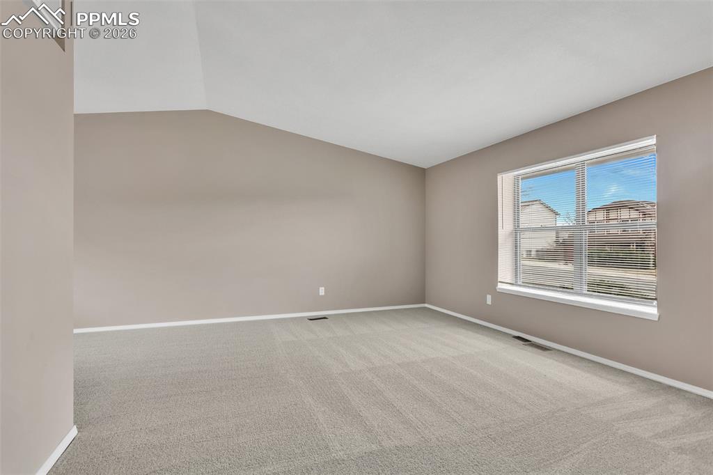 Image 3 of 30: Spare room featuring light colored carpet and vaulted ceiling