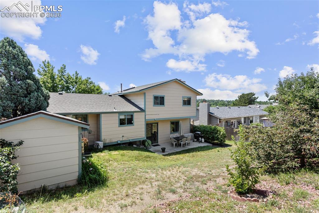 Image 30 of 30: Back of property with a patio area, a yard, a shed, and a shingled roof