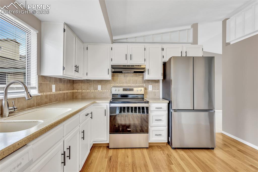 Image 8 of 30: Kitchen featuring stainless steel appliances, white cabinets, decorative ba