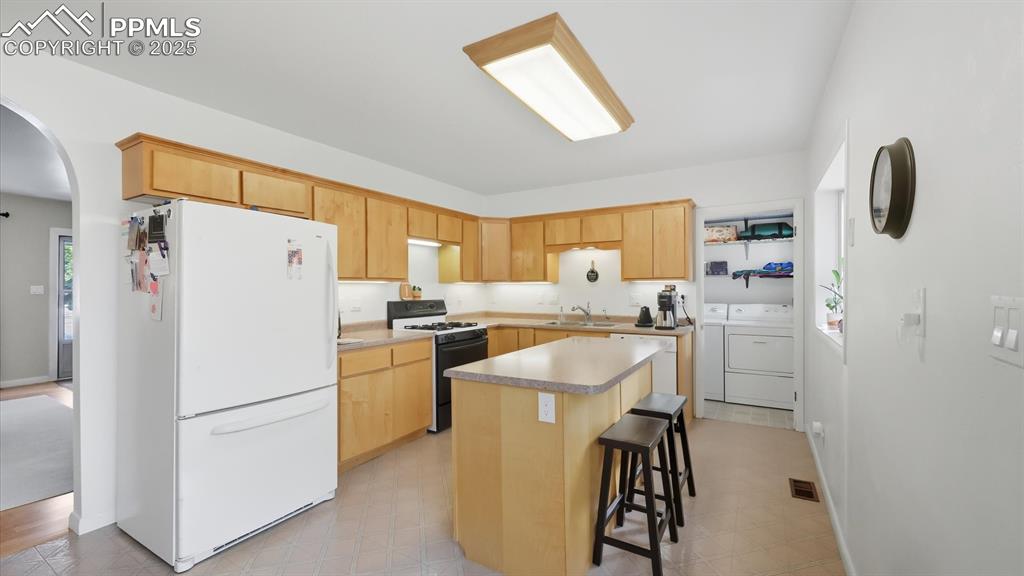 Image 17 of 34: The Island Kitchen features a breakfast bar, and ample wood cabinets with u