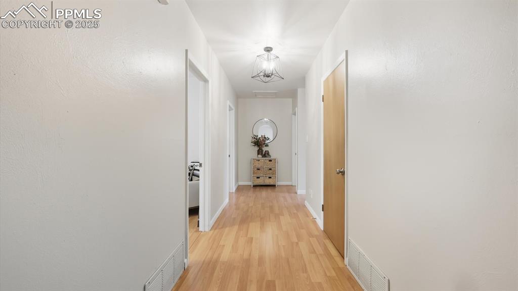 Image 22 of 34: Bedroom hallway with modern light fixture and wood laminate floor.