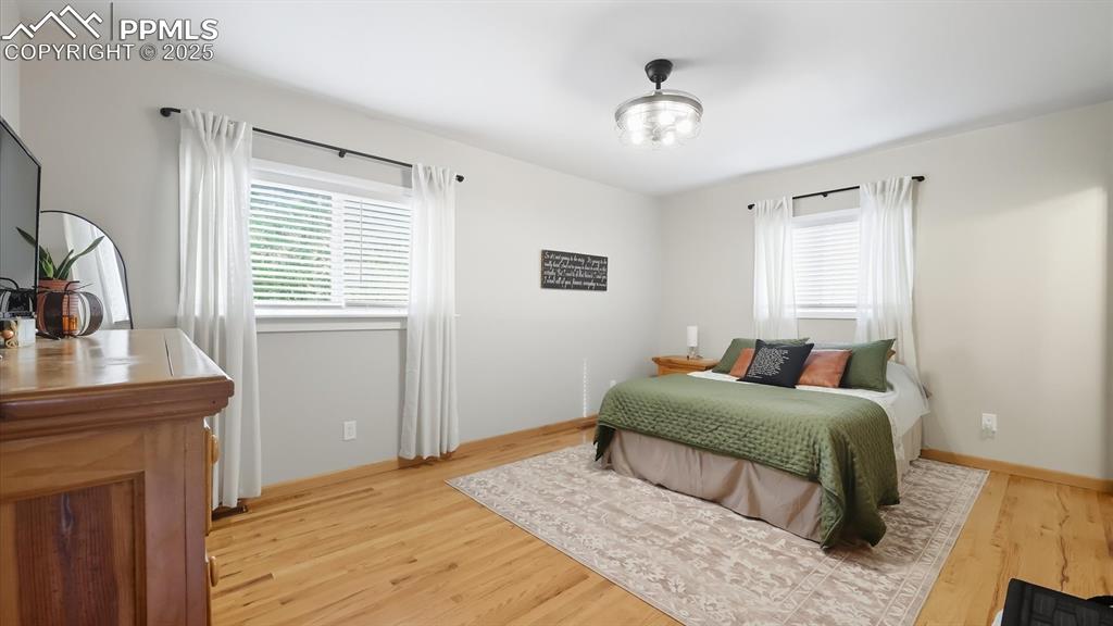 Image 25 of 34: Primary Bedroom with modern light fixture, wood laminate floor, and private