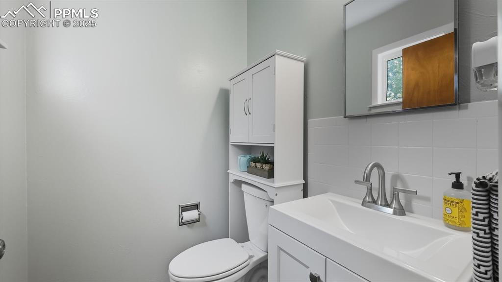 Image 28 of 34: Primary Half Bathroom with vanity, mirror, and toilet cabinet.