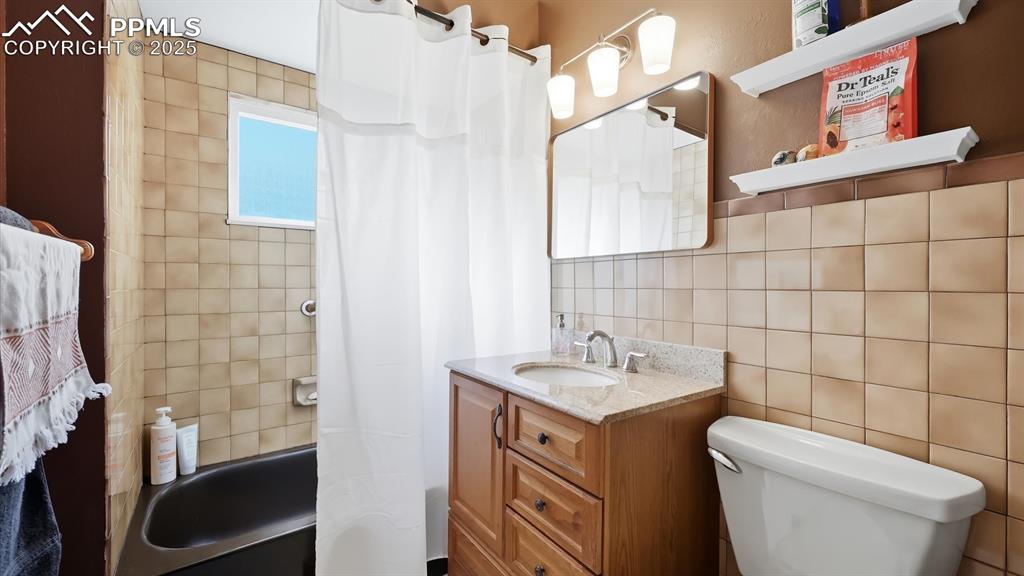 Image 31 of 34: Full Hall Bathroom with vanity, mirror, and tiled tub/shower.