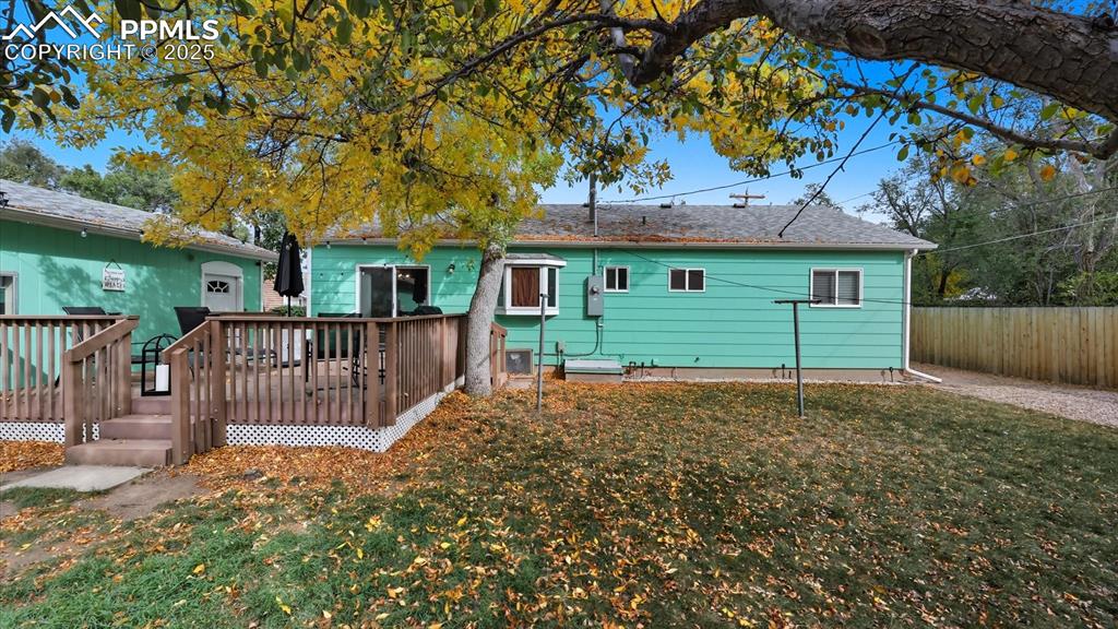 Image 33 of 34: Fenced backyard with mature trees for shade and composite deck for relaxati