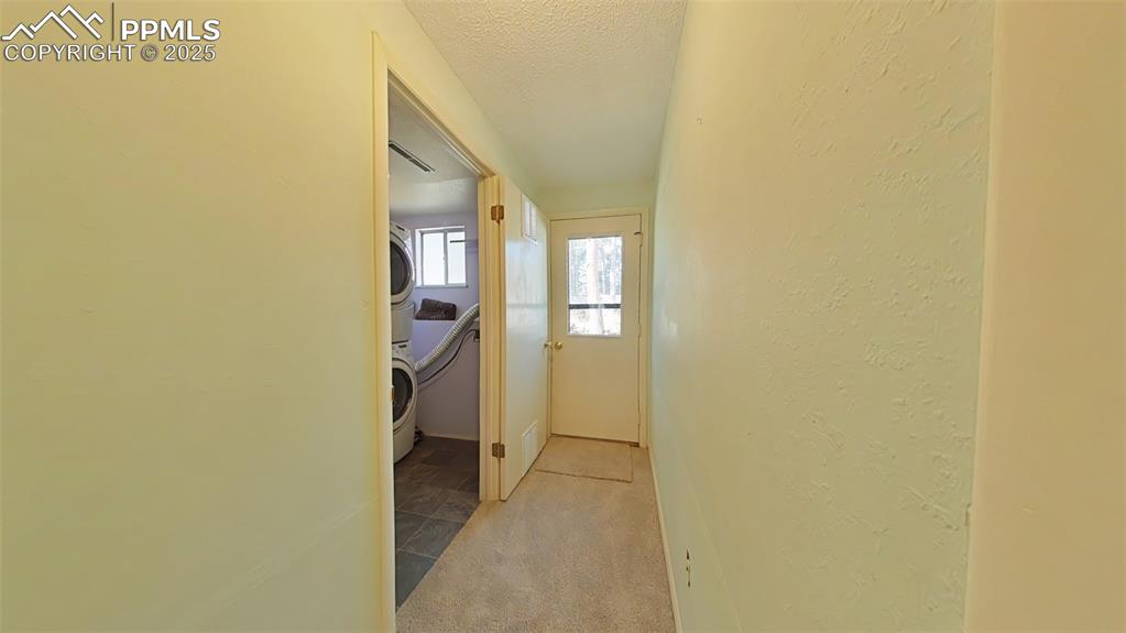 Image 22 of 25: Hallway featuring a light, carpet, a textured ceiling, a textured wall, and