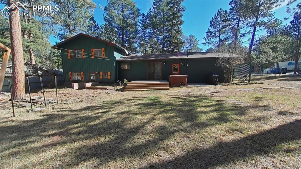 Image 25 of 25: Rear view of house featuring a wooden deck, a yard, board and batten siding