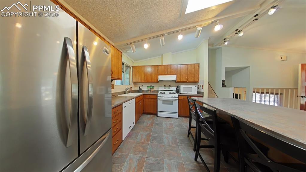 Image 6 of 25: Kitchen featuring white appliances, track lighting, a textured ceiling, ple