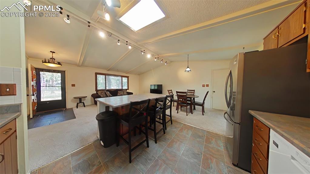 Image 7 of 25: Kitchen with brown cabinetry, dishwasher, a kitchen breakfast bar, freestan