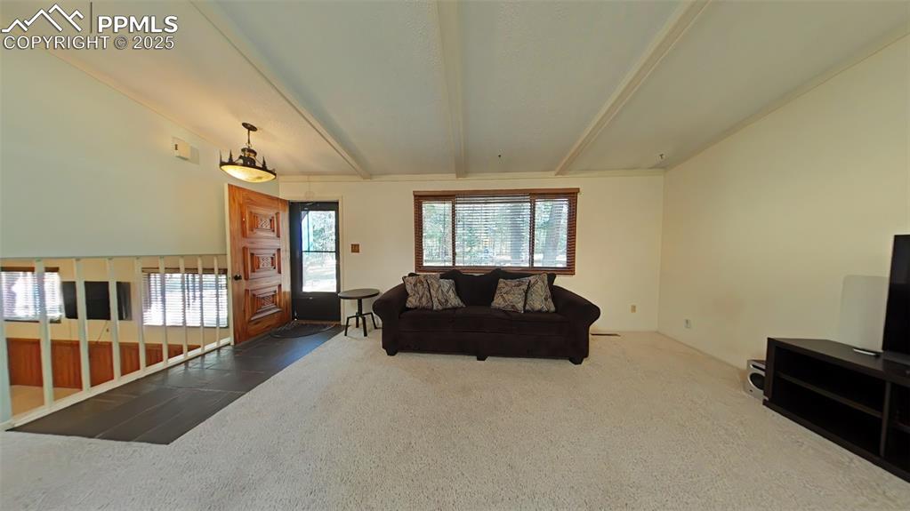 Image 9 of 25: Living area featuring beam ceiling and carpet