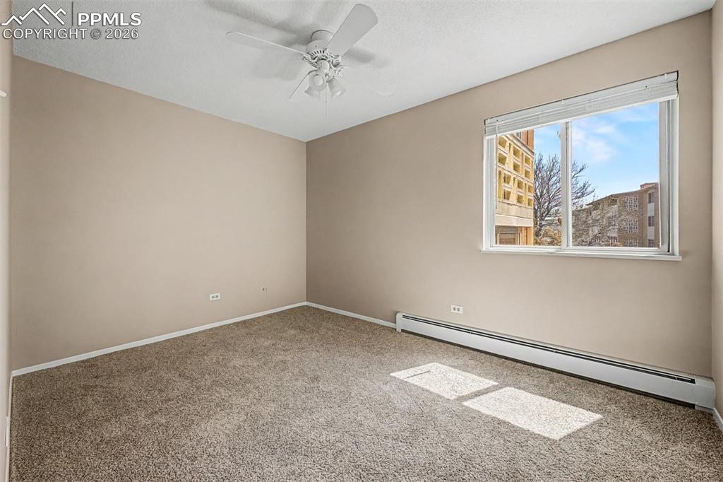 Image 11 of 42: Carpeted room featuring a ceiling fan, baseboard heating, a large window, a
