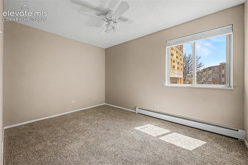 Image 14 of 50: Carpeted room featuring a ceiling fan, baseboard heating, a large window, a