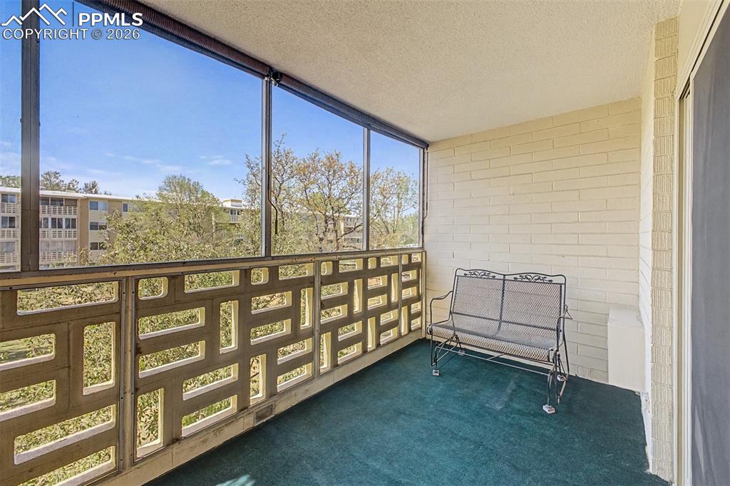 Image 20 of 42: Enclosed balcony featuring a patterned concrete screen wall, large windows,