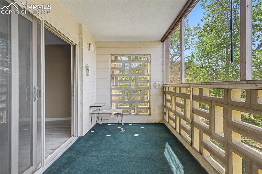 Image 21 of 42: Enclosed balcony featuring patterned concrete block walls, screening, and t