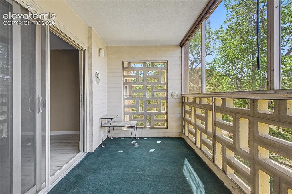 Image 27 of 50: Enclosed balcony featuring patterned concrete block walls, screening, and t