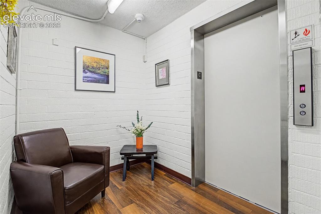 Image 29 of 50: Elevator access alongside a waiting area featuring wood-finish flooring, wh
