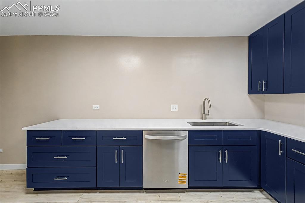 Image 3 of 42: Kitchen featuring blue shaker-style cabinetry, white countertops, stainless