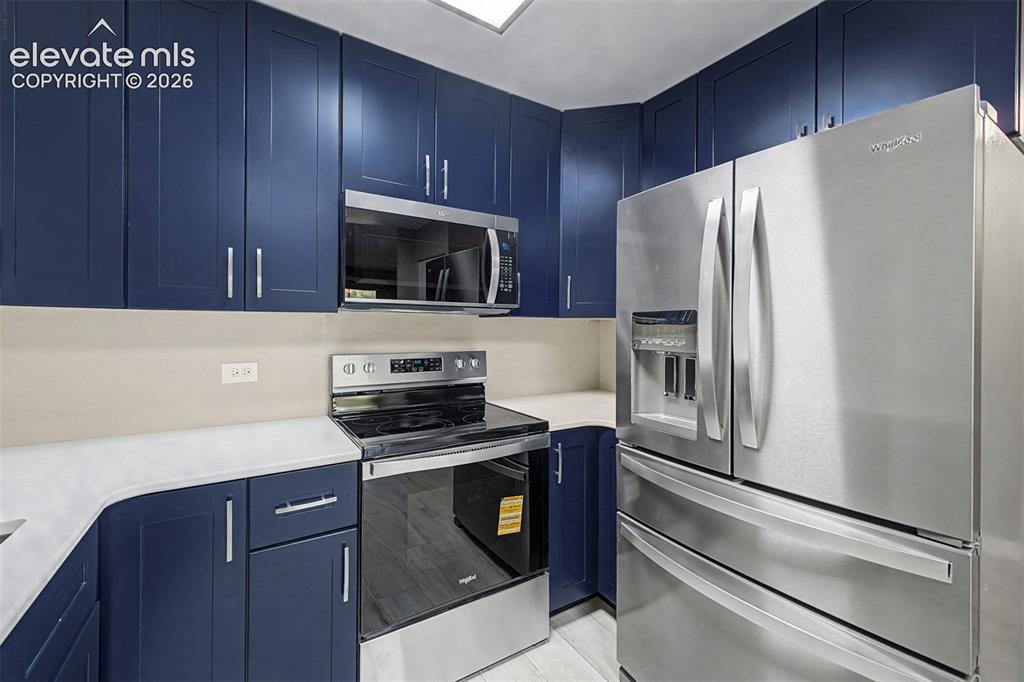 Image 3 of 50: Contemporary kitchen featuring navy blue cabinetry, stainless steel applian