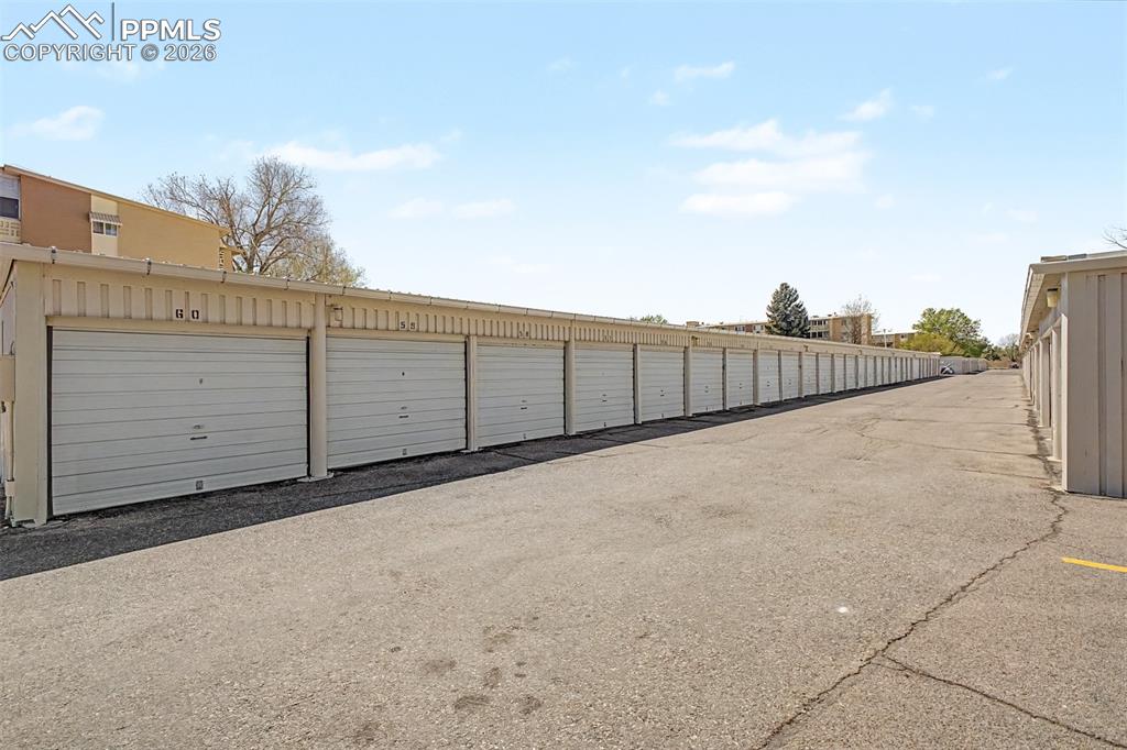 Image 34 of 42: Rows of individual garage units with light-colored roll-up doors, metal sid