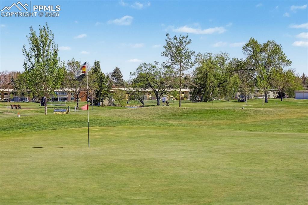 Image 36 of 42: Expansive green golf course featuring a putting green with a flagstick, mat