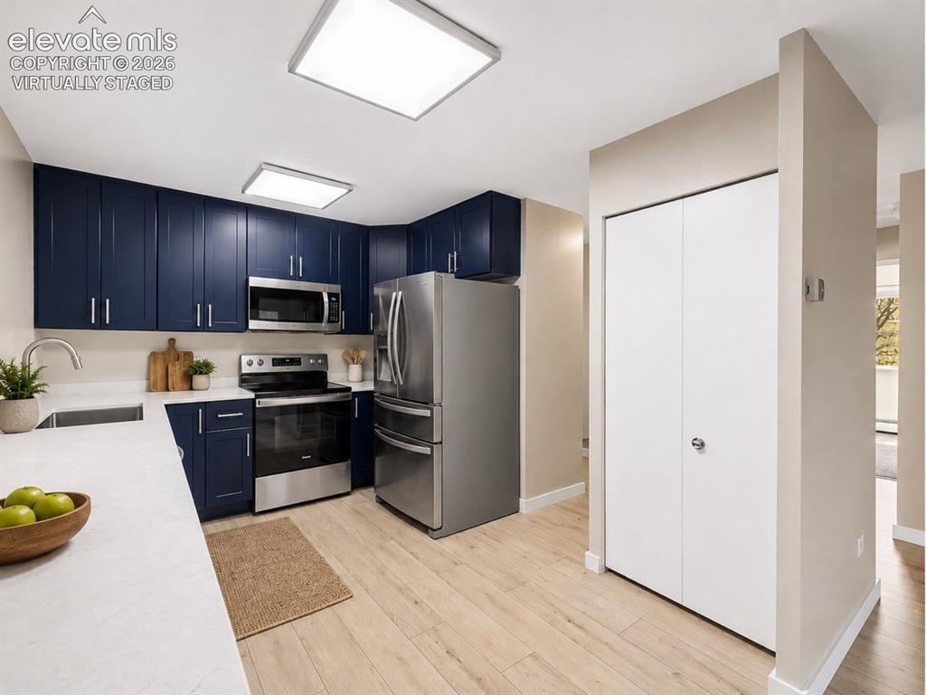 Image 4 of 50: virtually staged Contemporary kitchen with navy cabinetry, light countertop