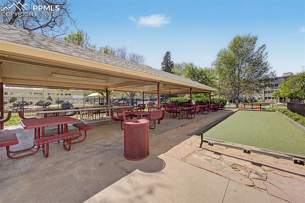 Image 40 of 42: Covered outdoor patio area featuring multiple picnic tables with attached b