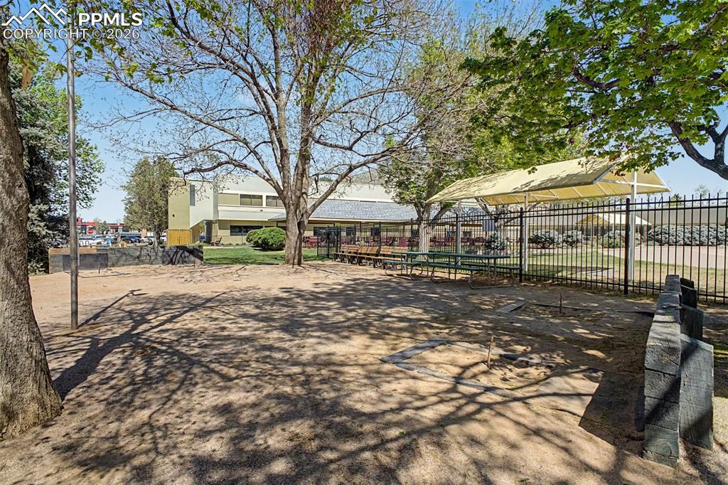 Image 42 of 42: Outdoor area featuring a fenced perimeter, a shade structure, and picnic ta