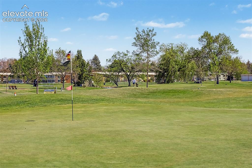 Image 44 of 50: Expansive green golf course featuring a putting green with a flagstick, mat
