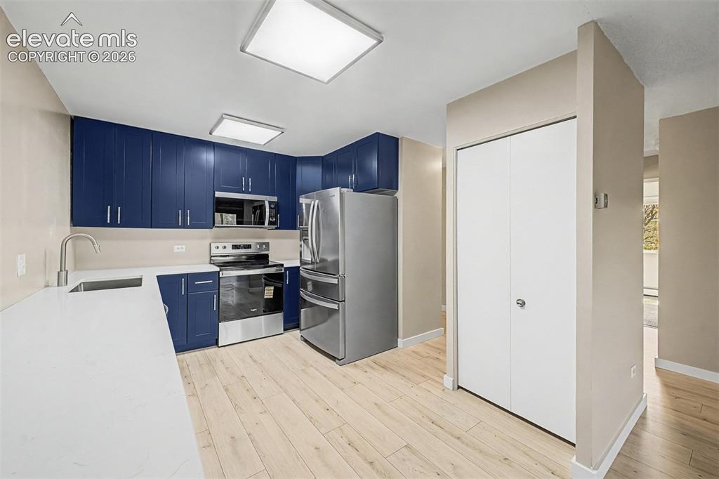 Image 5 of 50: Kitchen featuring wood-finish flooring, white countertops, and blue cabinet