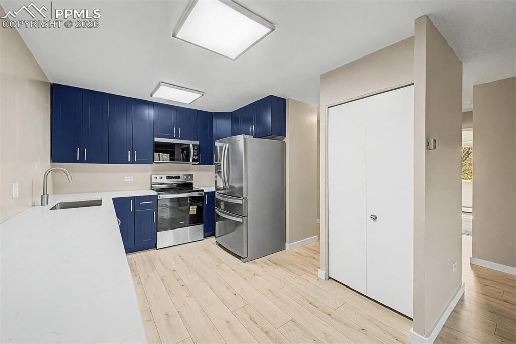 Image 7 of 42: Kitchen featuring wood-finish flooring, white countertops, and blue cabinet