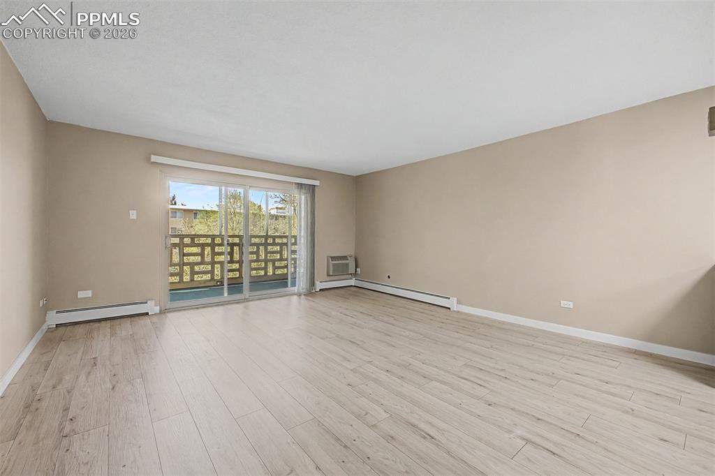Image 9 of 42: Spacious room featuring light wood-finish flooring, neutral wall tones, and