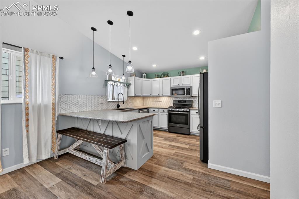Image 17 of 47: Kitchen featuring stainless steel appliances, a peninsula, lofted ceiling,