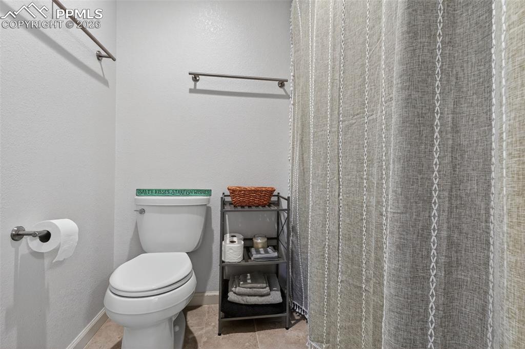 Image 25 of 47: Bathroom featuring a shower with shower curtain, a textured wall, and light