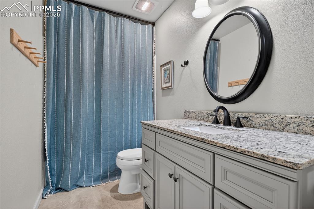 Image 30 of 47: Bathroom featuring vanity, a textured wall, and a shower with shower curtai
