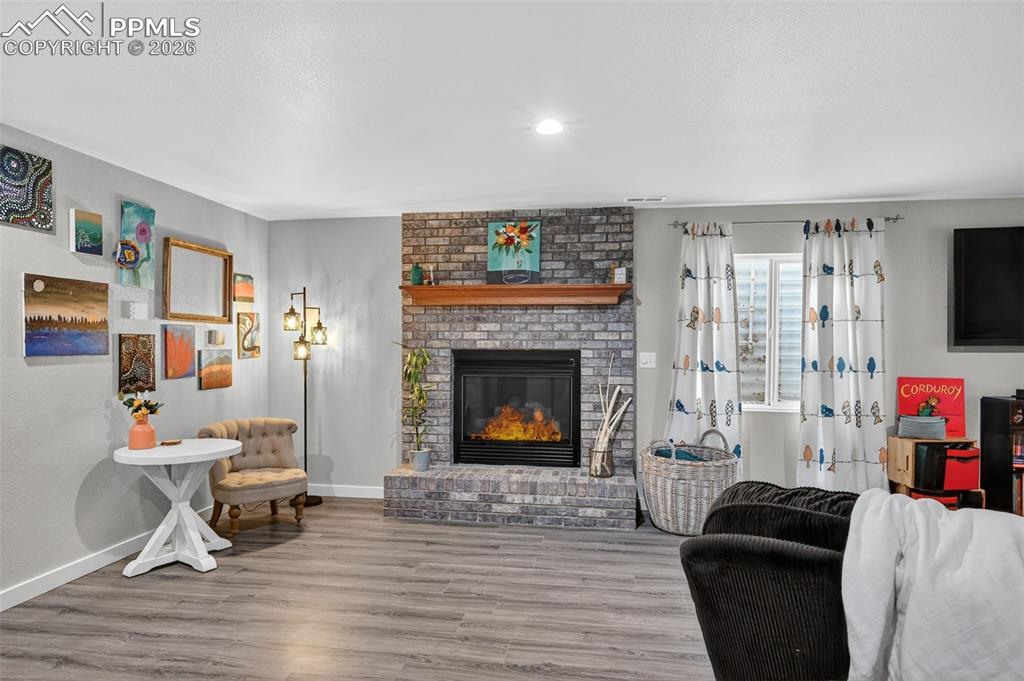 Image 33 of 47: Living room featuring wood finished floors, a brick fireplace, and recessed