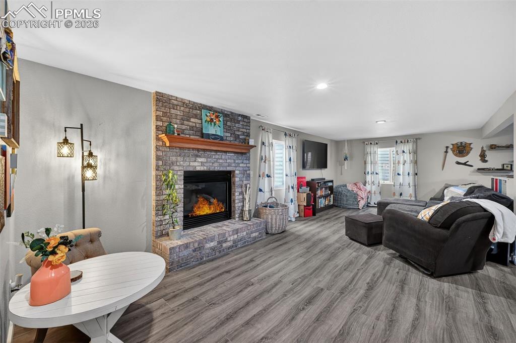 Image 34 of 47: Living room featuring wood finished floors, a brick fireplace, and recessed