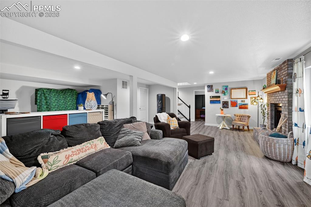 Image 37 of 47: Living room with a brick fireplace, wood finished floors, recessed lighting