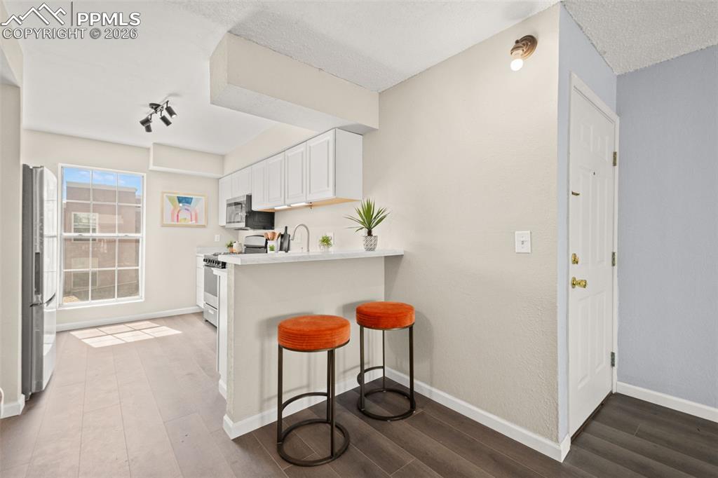 Image 12 of 27: Kitchen area featuring white cabinetry, stainless steel appliances, a white