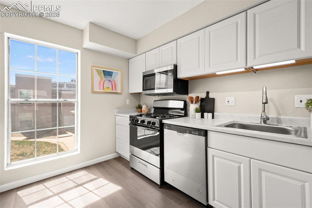 Image 14 of 27: The kitchen features white cabinetry, stainless steel appliances, and sleek