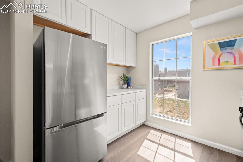Image 15 of 27: Kitchen featuring white cabinetry, a stainless steel refrigerator, and a wi