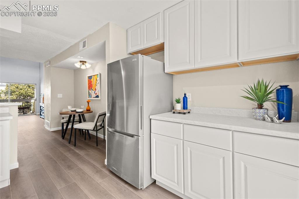 Image 16 of 27: The kitchen features white cabinetry, a stainless steel refrigerator, and a