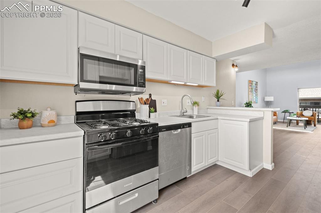 Image 17 of 27: The kitchen features white cabinetry, a stainless steel microwave, a stainl