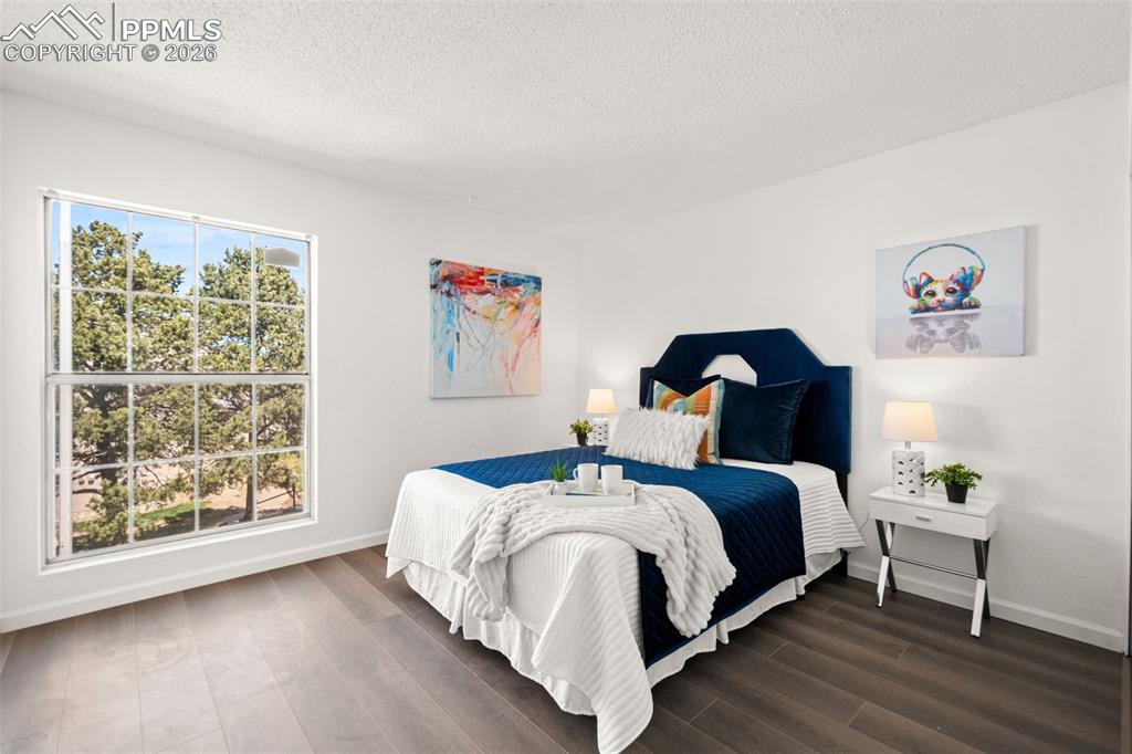 Image 21 of 27: This room features light-colored walls and dark hardwood floors, creating a
